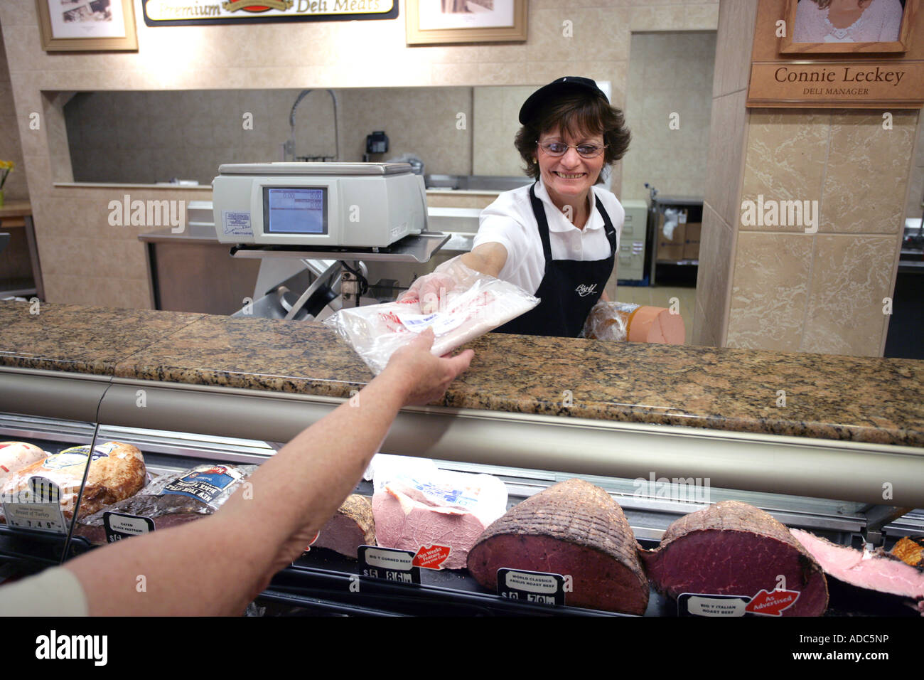 Un commis de charcuterie en tranches d'un client mains la viande froide