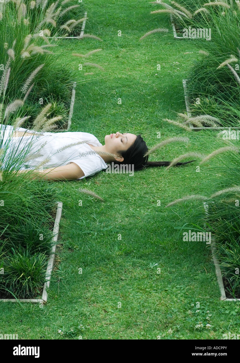 Femme couchée sur l'herbe, les yeux fermés Banque D'Images
