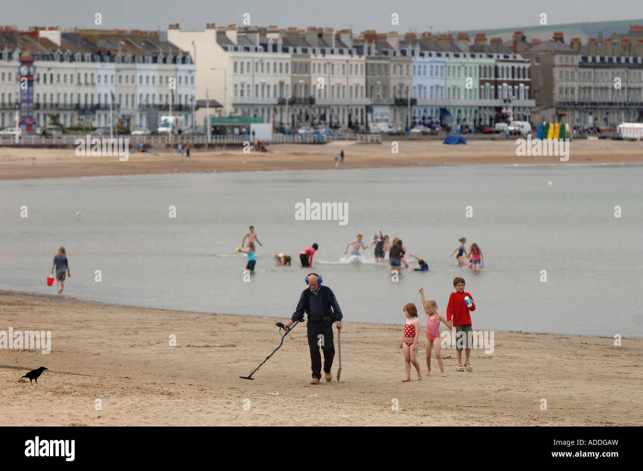 Un homme avec un détecteur de métal à monter et descendre la plage de Weymouth, Dorset, UK, à la fin de la journée. Banque D'Images