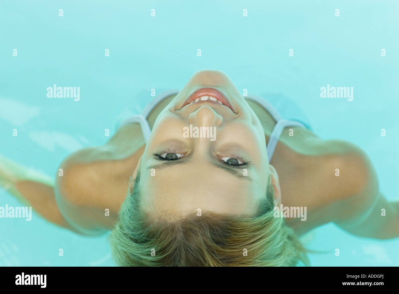 Jeune femme dans la piscine, smiling at camera, vue à partir de juste au-dessus Banque D'Images