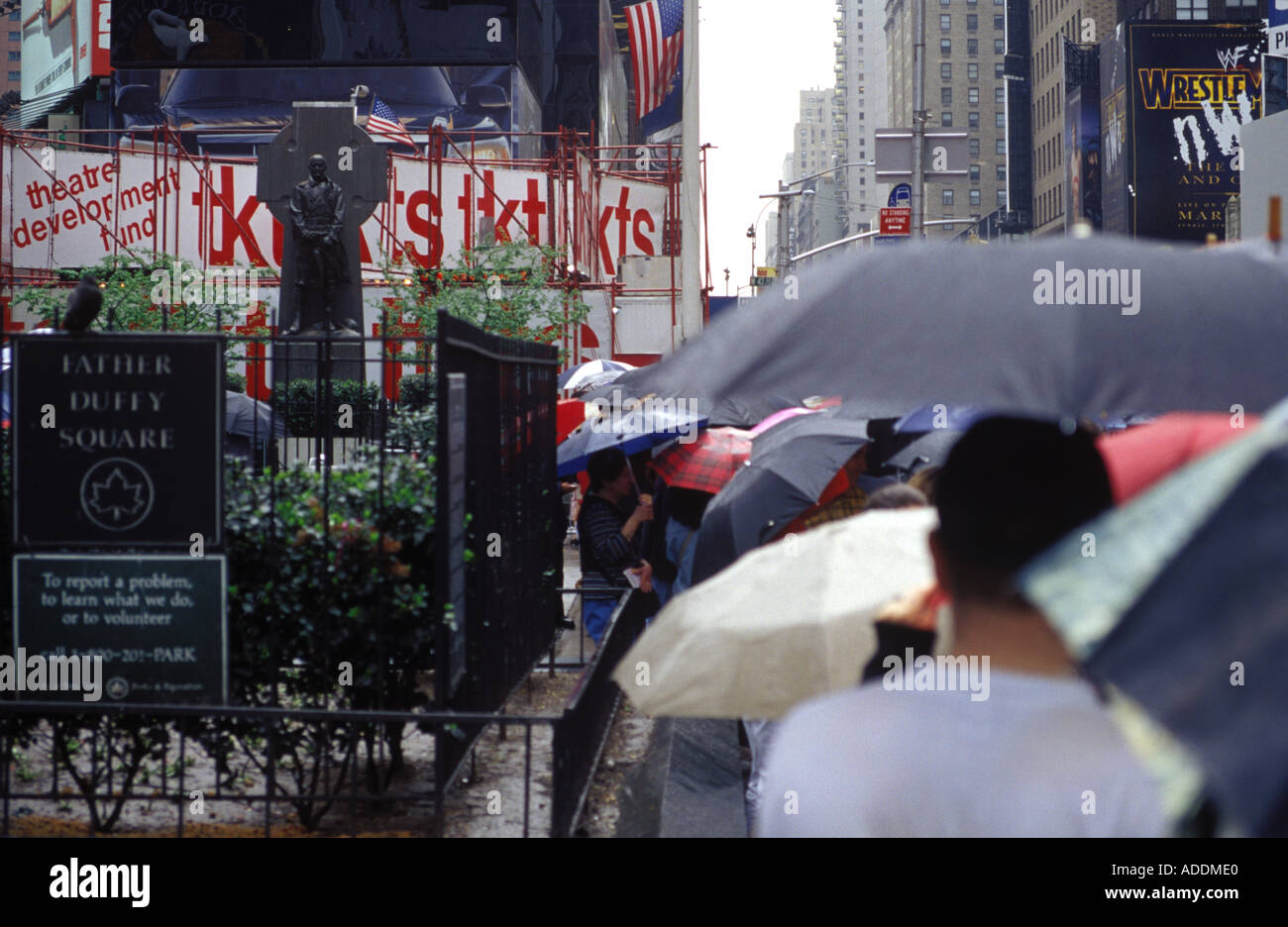 La queue dans la pluie des places de théâtre à Times Square à New York City Banque D'Images