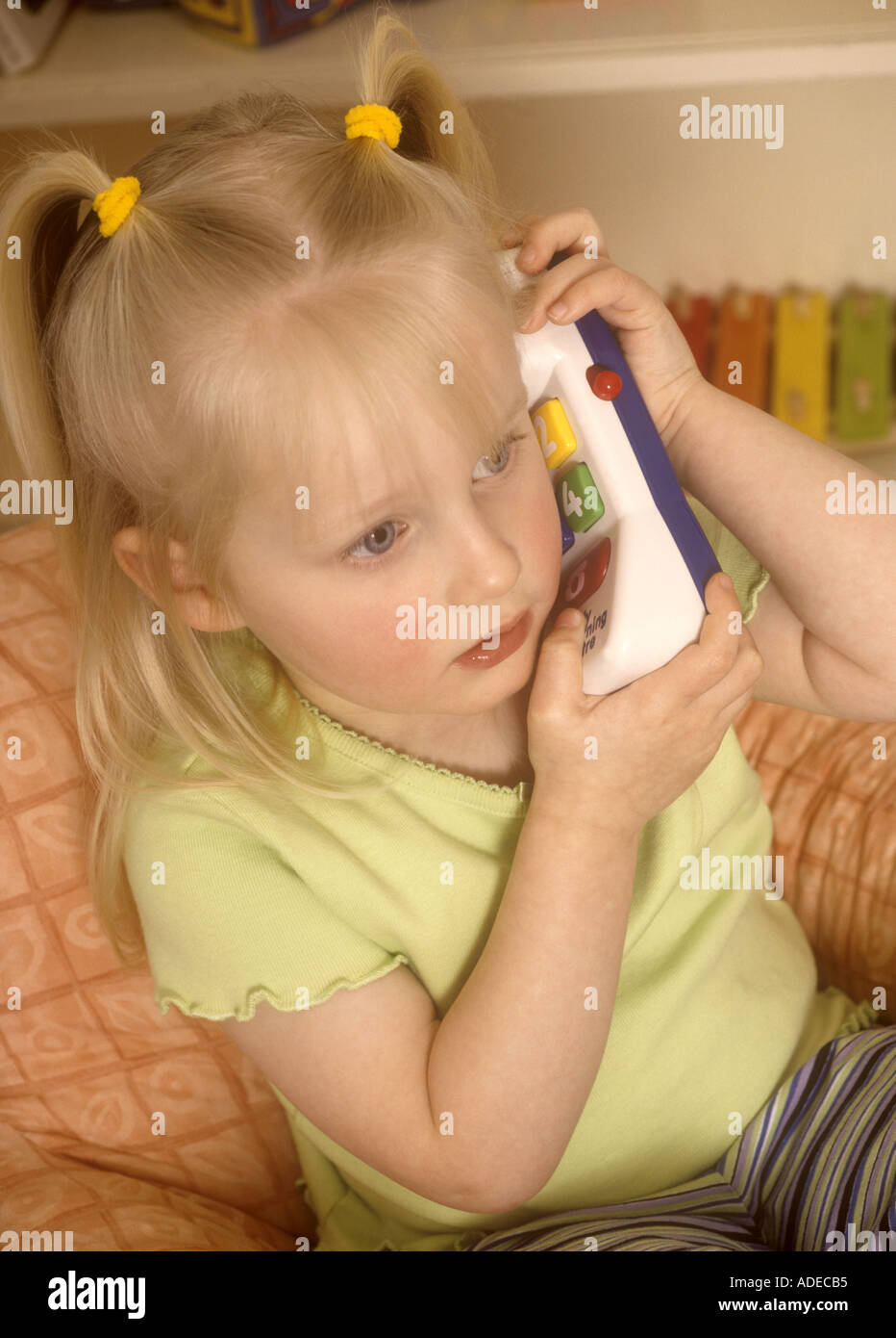 Jeune fille jouant avec des jouets en plastique téléphone Banque D'Images