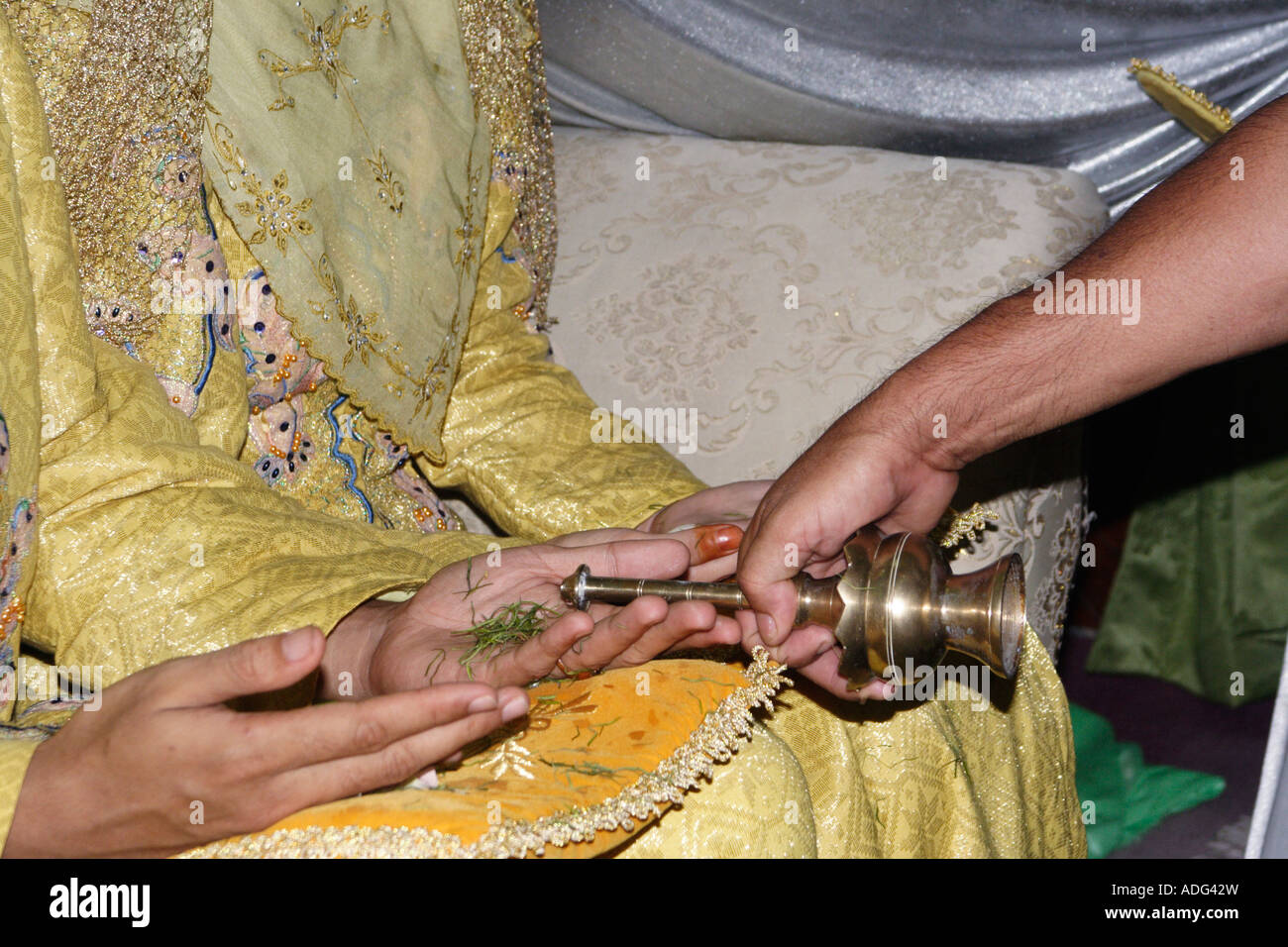 Projections d'eau parfumée sur la paume ouverte de l'époux et épouse au cours d'une cérémonie de mariage malais en Malaisie. Banque D'Images