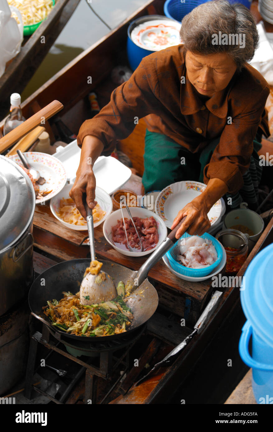 Femme thaïlandaise prépare la nourriture sur un sampan au marché flottant de Damnoen Saduak près de Bangkok en Thaïlande Banque D'Images