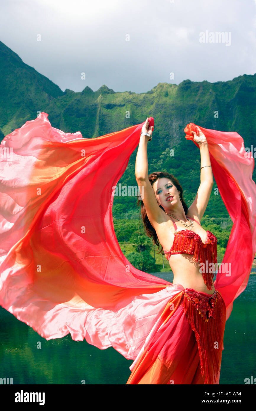 Danseuse du Ventre avec voile rouge, bras tendus au décor tropical Photo  Stock - Alamy