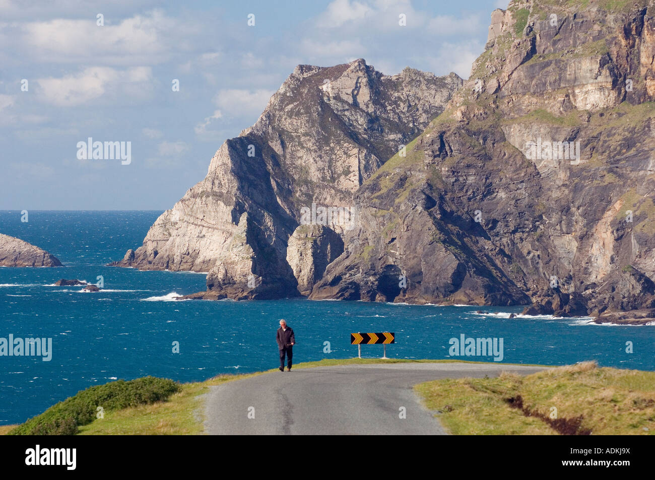 Homme marchant sur la route au sud de Greeneville à Malin Beg, le sud-ouest de comté de Donegal, Irlande. Falaises de Glen tête derrière. Banque D'Images