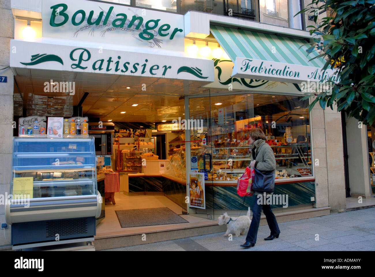 Woman walking dog passé Boulanger pâtissier en Street à Caen. Normandie, France. Banque D'Images