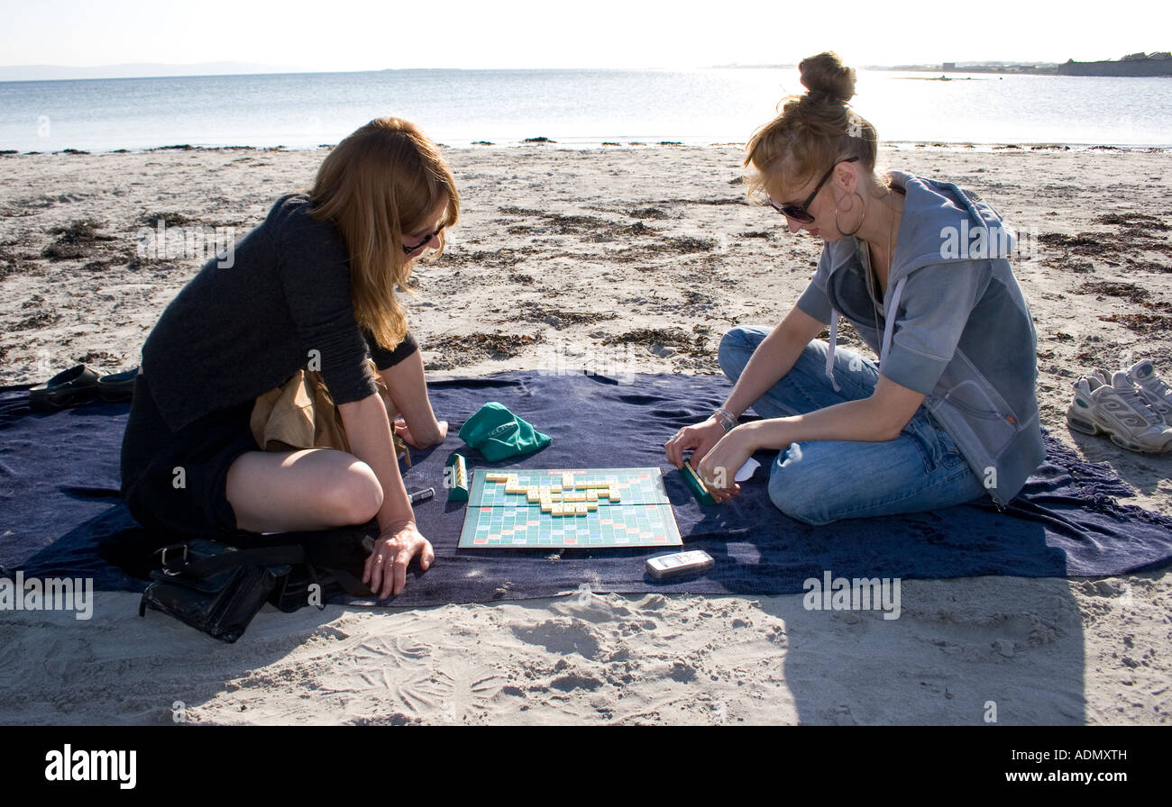 Mère et fille jouant au Scrabble sur une plage, la baie de Galway, Irlande Banque D'Images