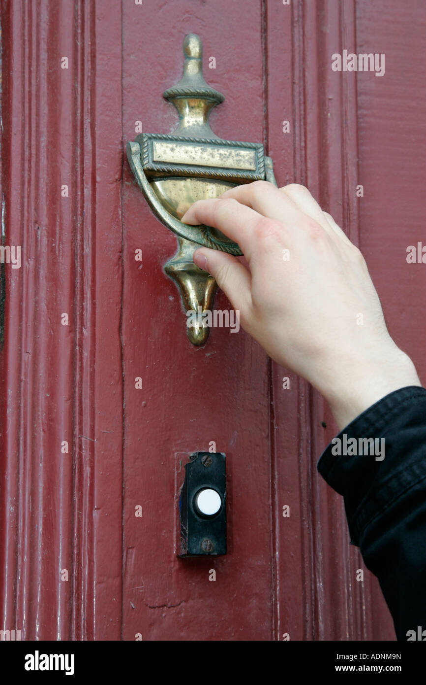 Mans la main à l'aide d'heurtoir de porte en bois au lieu d'appeler à froid ménage bell Banque D'Images