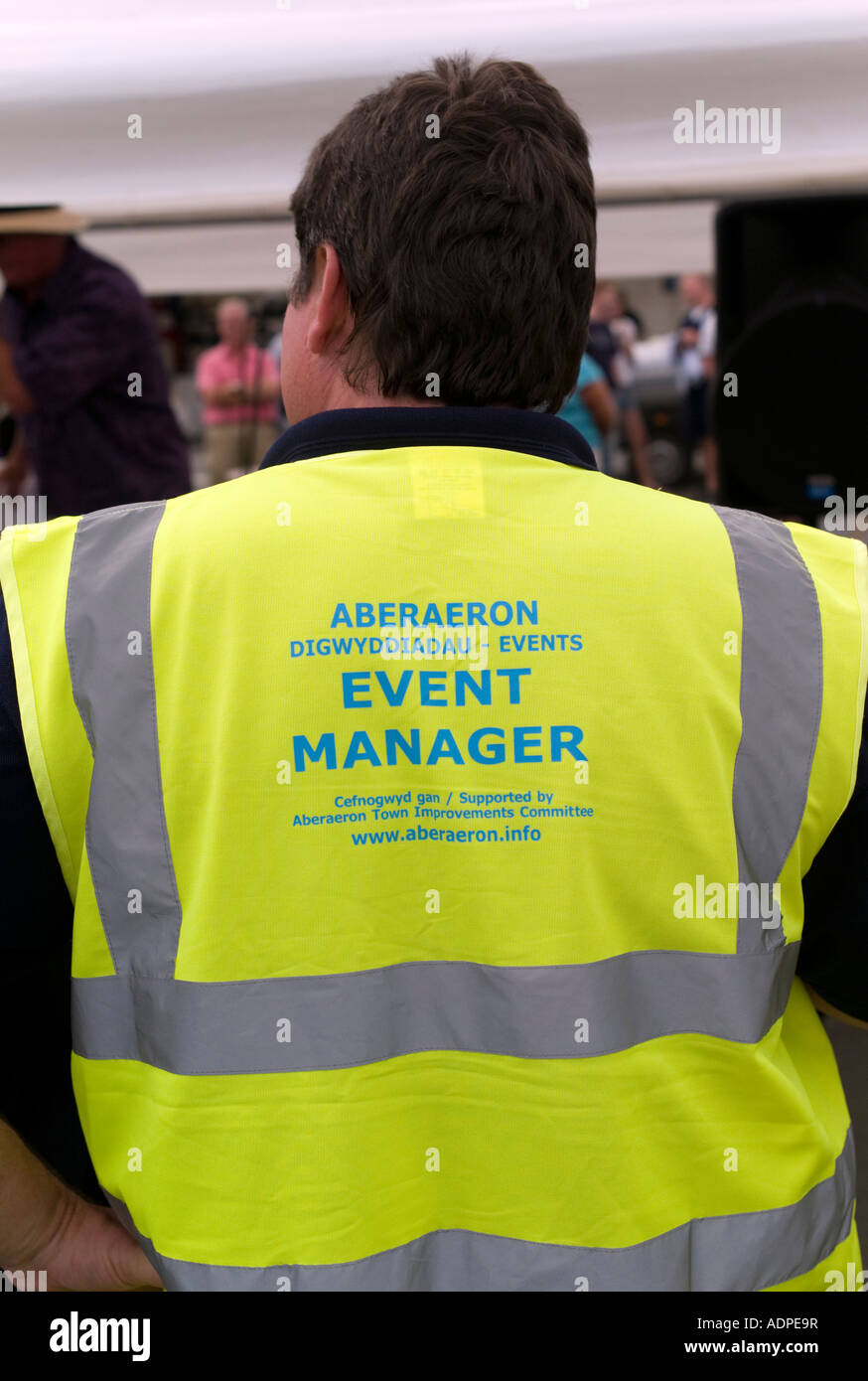 Vue arrière d'un homme portant le gestionnaire d'événements à haute visibilité jaune tabard vest event manager contrôle de la foule Banque D'Images