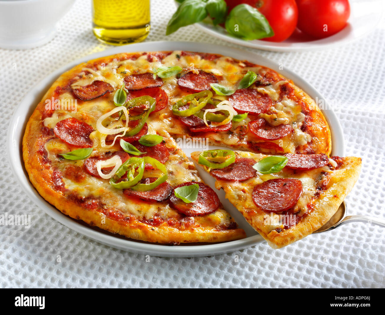 Pizza garnie de pepperoni, piment et basilic Banque D'Images