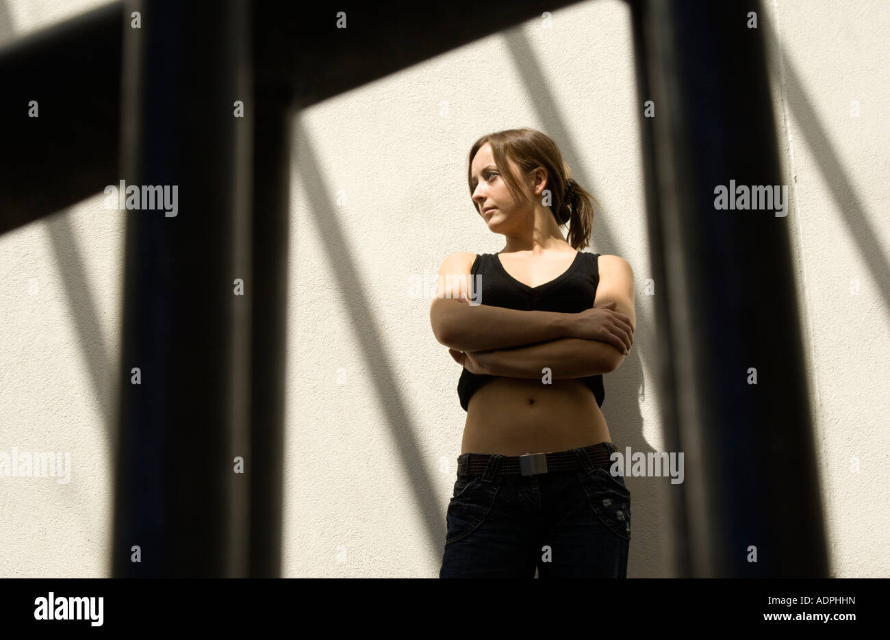 Jeune femme à l'intérieur avec les ombres de formes graphiques casting windows sur mur derrière elle à comme Banque D'Images
