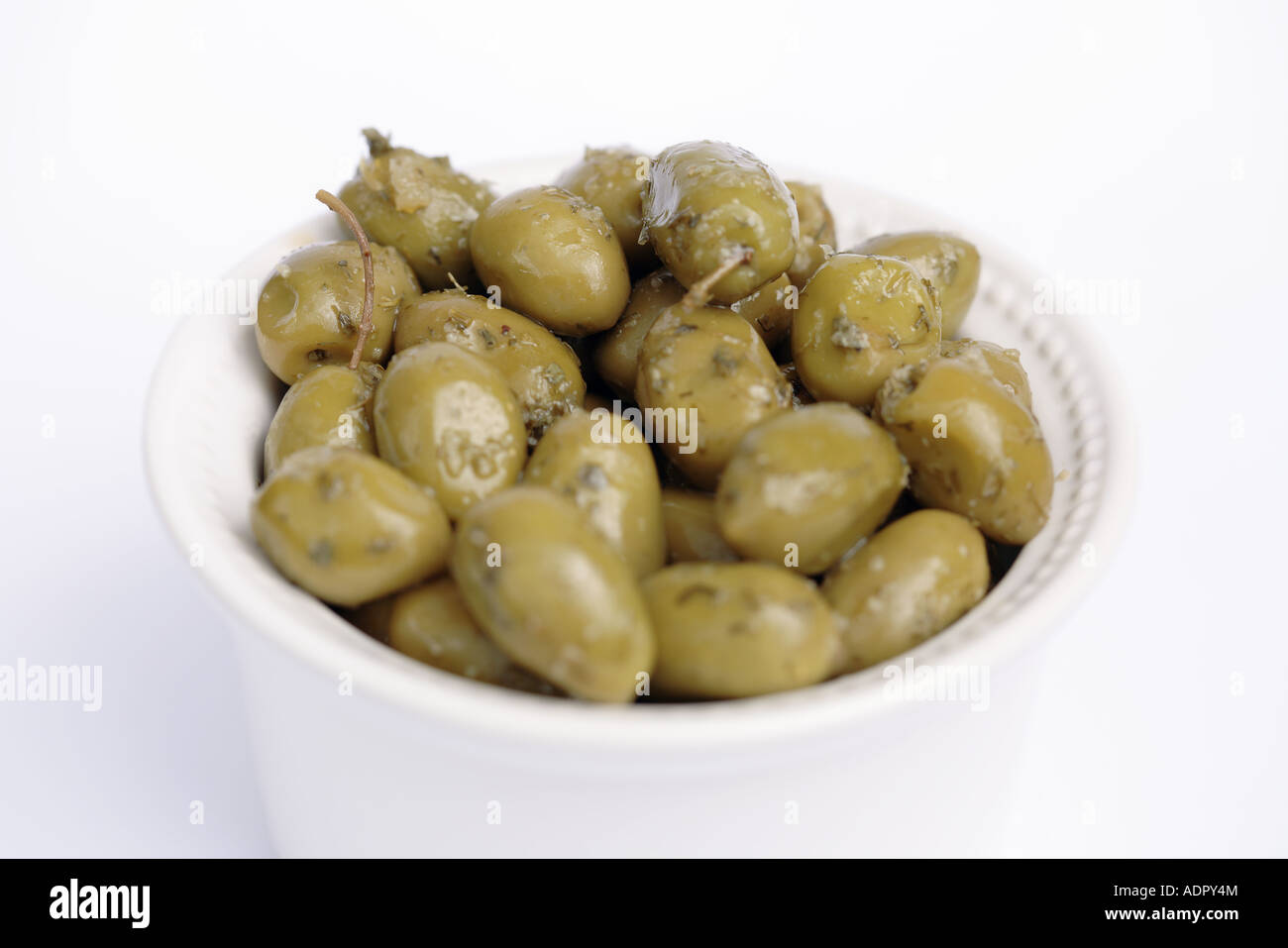 Olives vertes aux herbes dans un bol blanc Banque D'Images