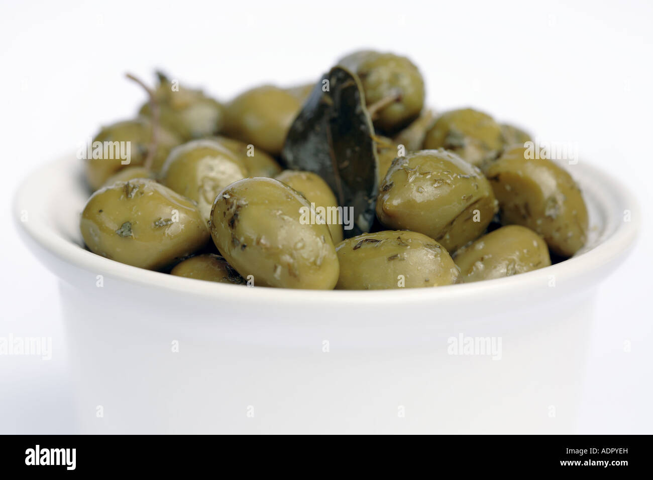 Olives vertes aux herbes dans un bol blanc Banque D'Images