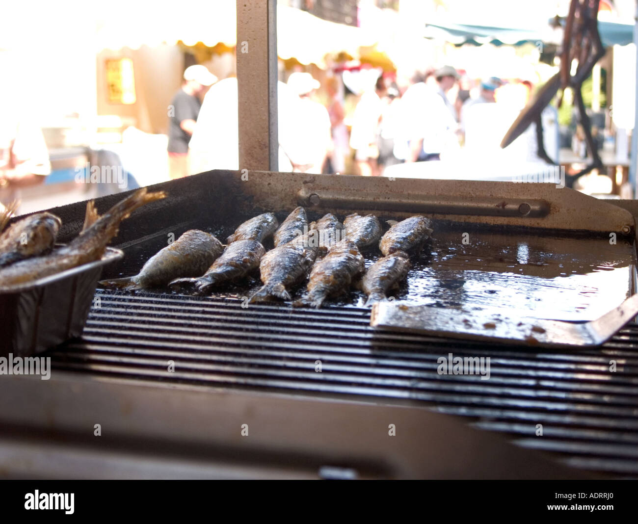 Close up de griller les sardines avec vue brouillée de foules en arrière-plan Banque D'Images