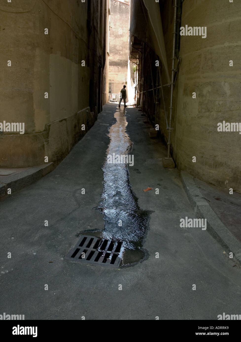 Un homme seul marche si une fuite d'eau dans une ruelle sombre Banque D'Images