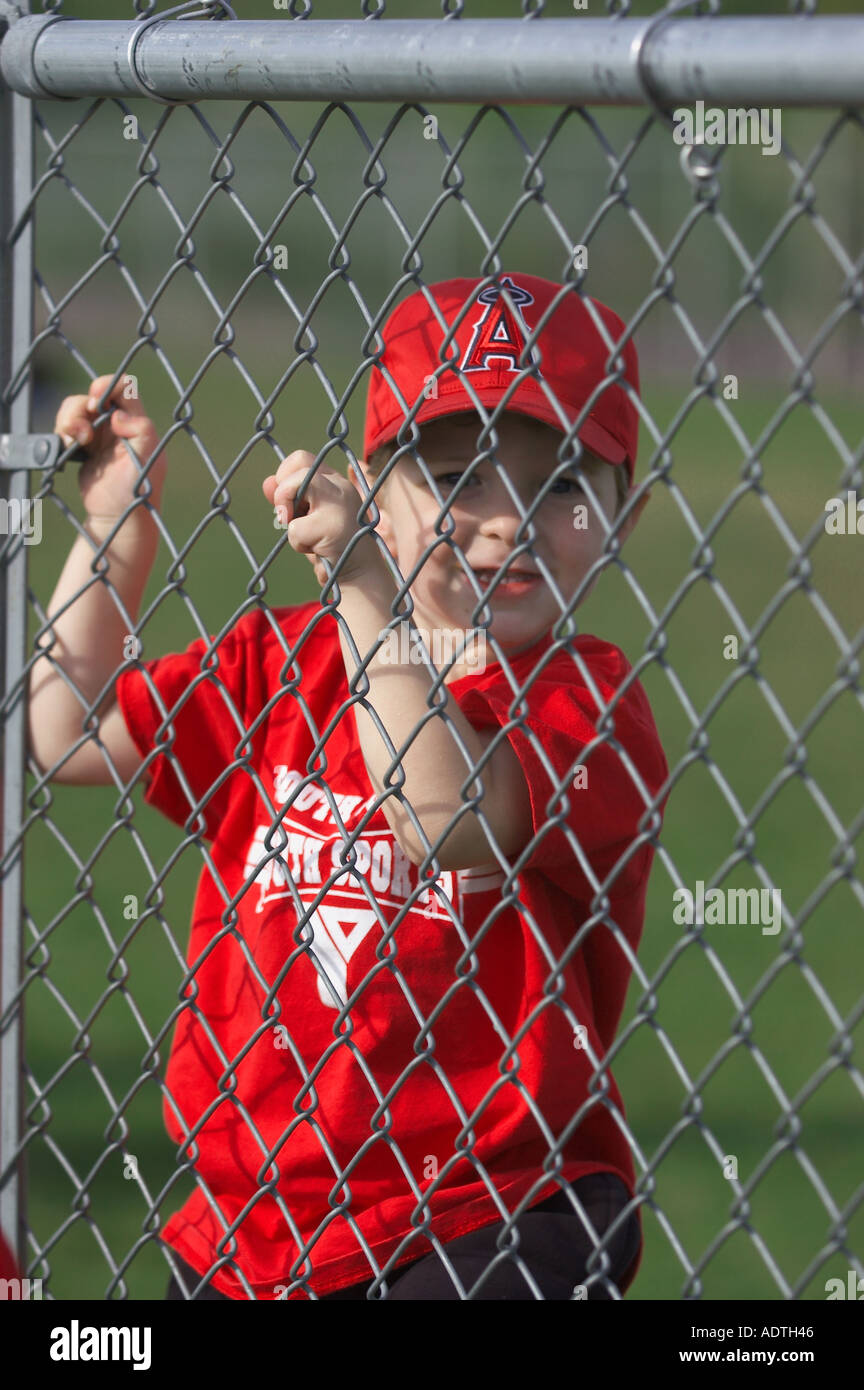 Le base-ball boy accrochant sur fence Banque D'Images