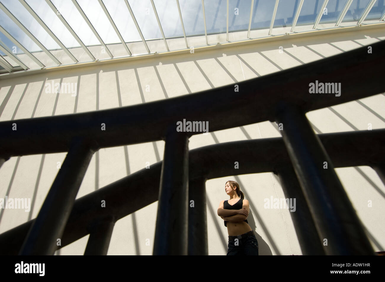 Jeune femme à l'intérieur avec les ombres de formes graphiques casting windows sur mur derrière elle Banque D'Images
