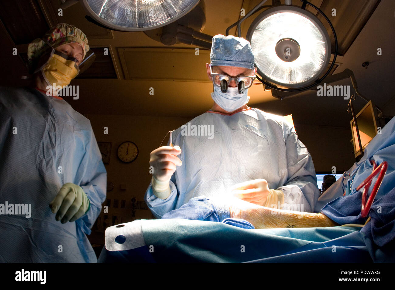 Chirurgien vasculaire effectue une procédure sur un poignet du patient alors que l'aide d'une infirmière en salle d'opération Banque D'Images