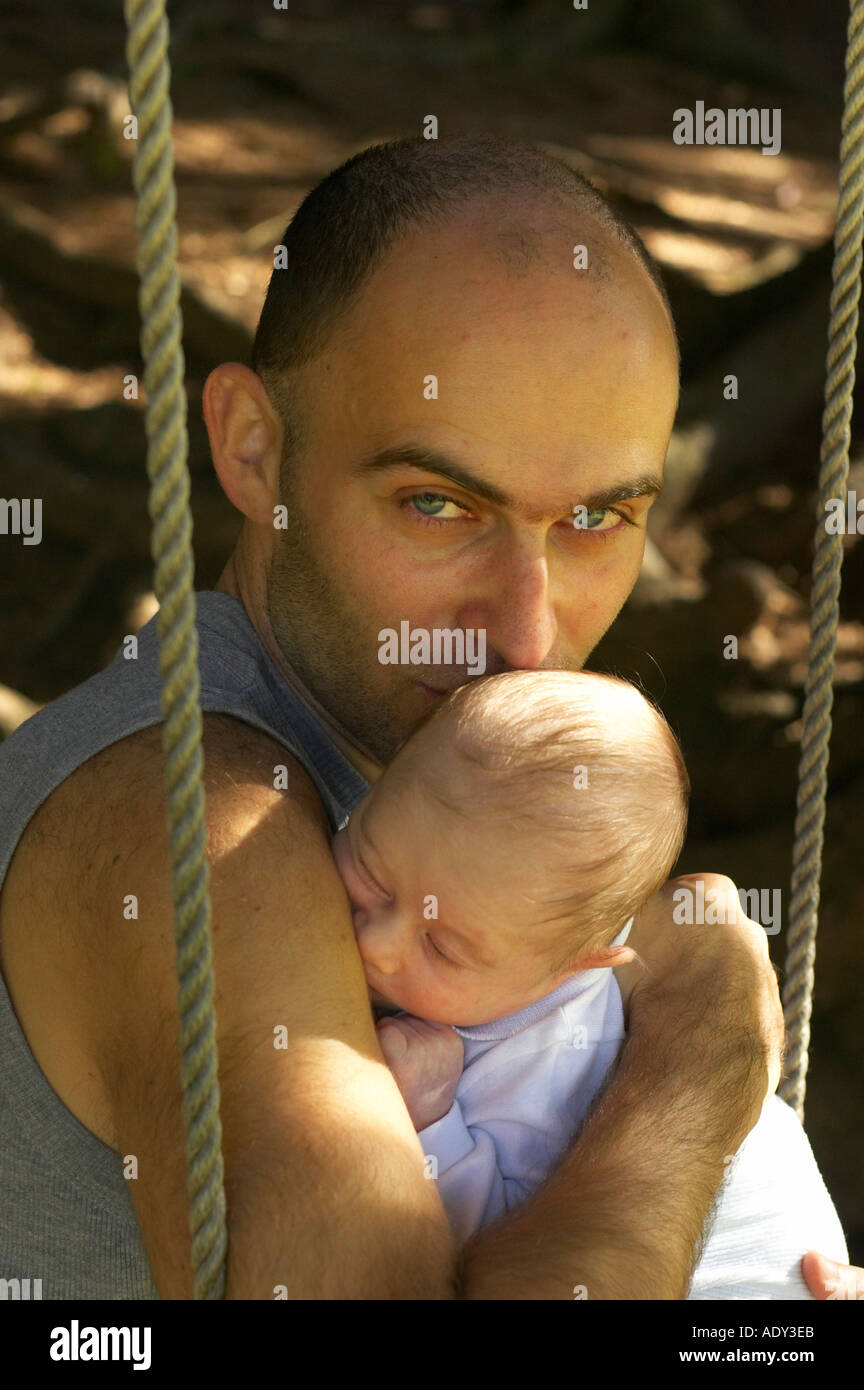 Homme assis avec bébé on swing Banque D'Images