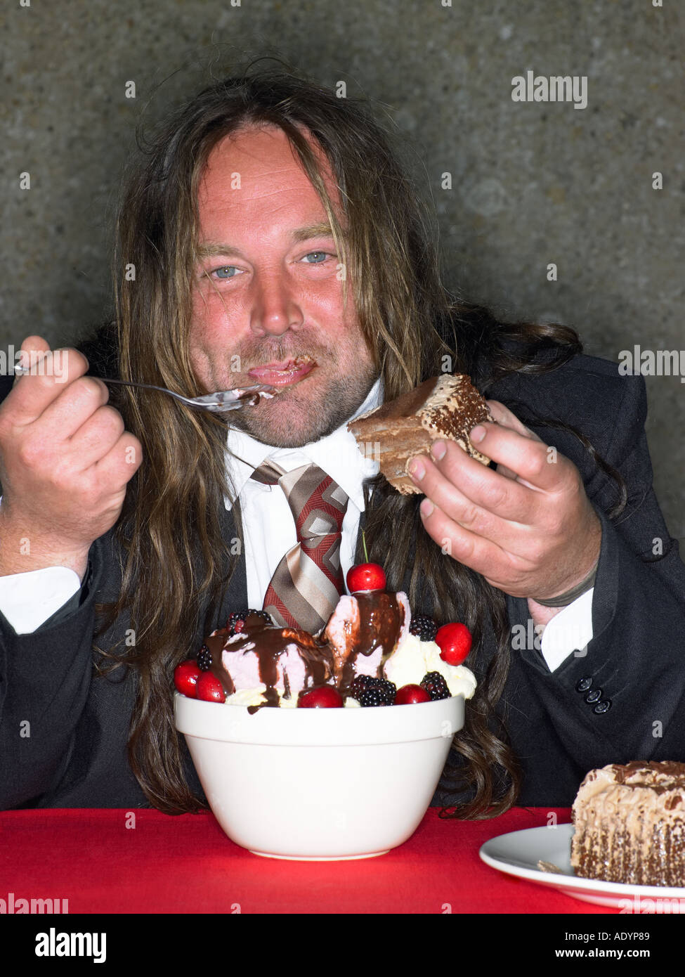 Gros homme aux cheveux longs manger bouche lui-même avec de la crème glacée Banque D'Images