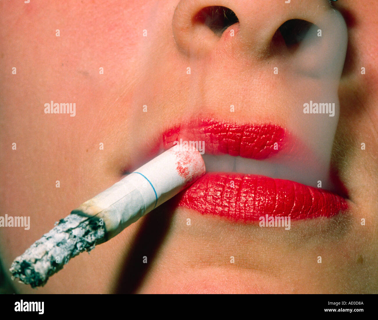 Bouche d'une jeune femme avec la cigarette et la fumée Photo Stock