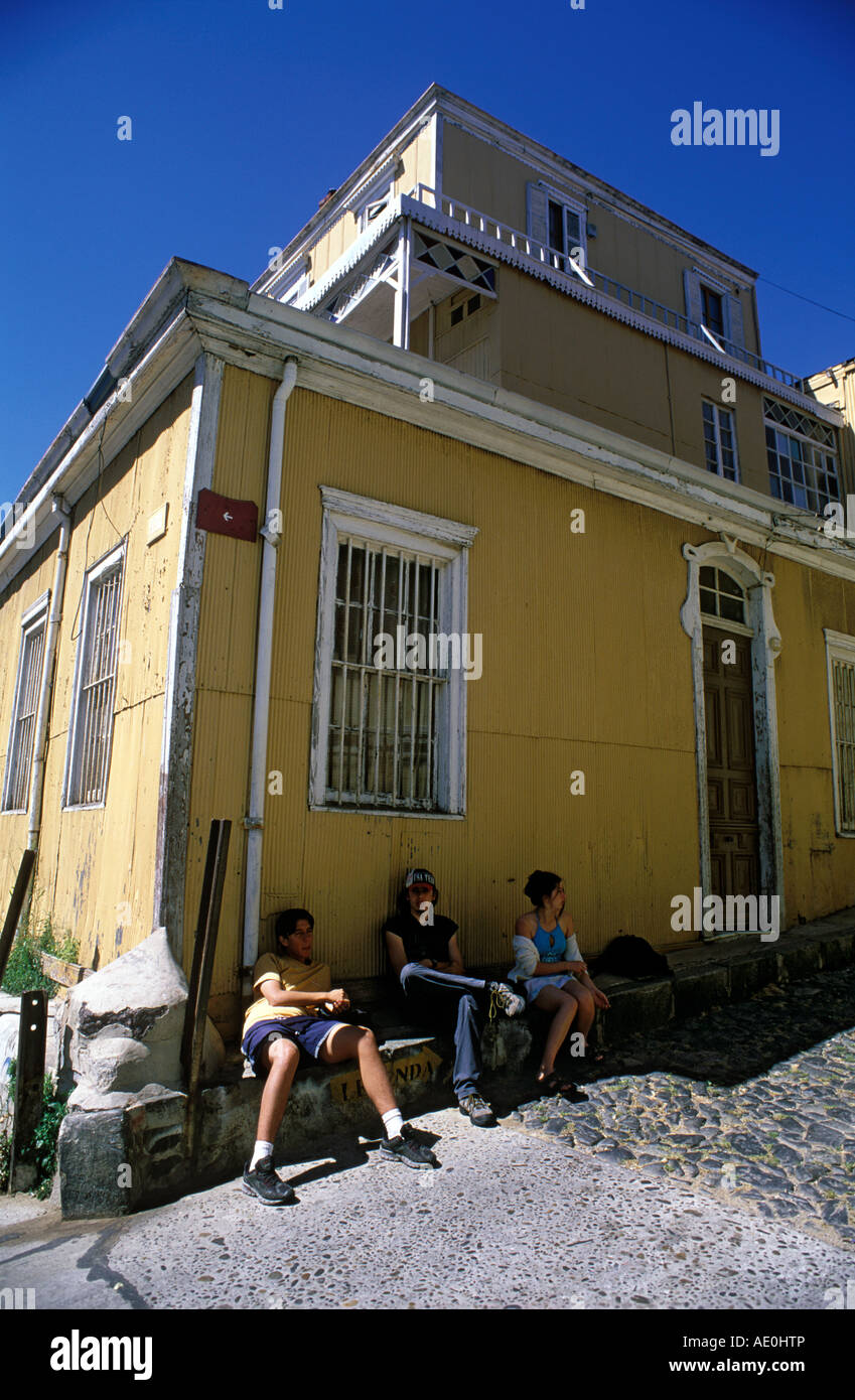 Trois adolescents s'asseoir sur les marches d'un revêtement en tôle ondulée, maison dans la banlieue de la colline Cerro Conception, Valparaiso, Chili. Banque D'Images