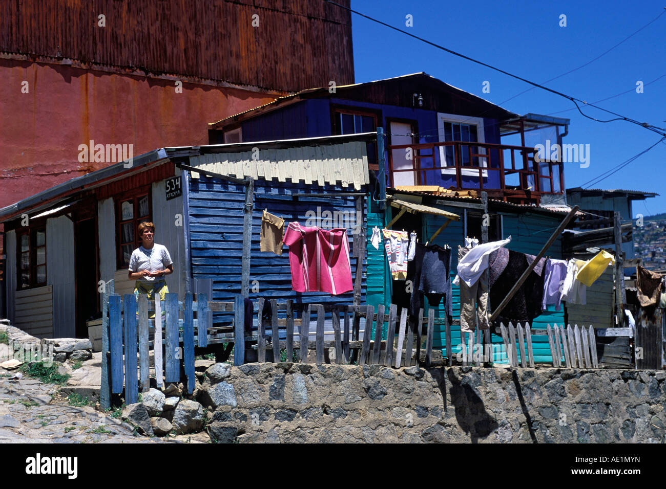 Une femme debout devant sa maison en bois dans l'ancien quartier au sommet de la colline de Cerro Conception, Valparaiso, Chili. Banque D'Images