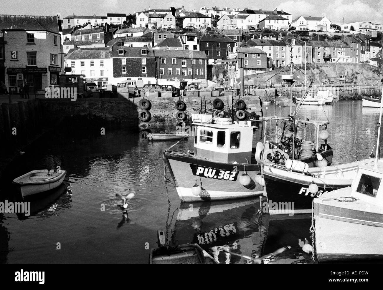 Mevagissey Harbour en noir et blanc avec des bateaux de pêche à l'ancre avec gîtes traditionnels seagull taking off Banque D'Images