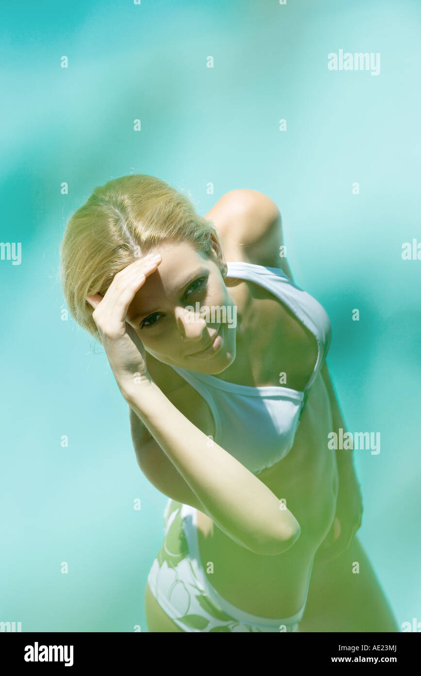 Young woman in bikini, l'ombrage des yeux, looking at camera Banque D'Images