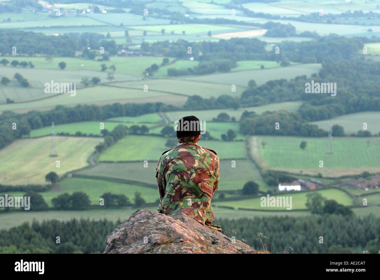 Jeune homme portant veste de camouflage à la recherche de paysage à la colline Wrekin, Shropshire England UK Banque D'Images