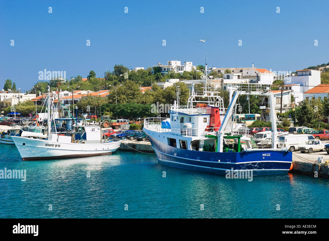 Un bleu et un bateau blanc au port de Kamariotisa Samothraki island avec le village à l'buckhound Banque D'Images