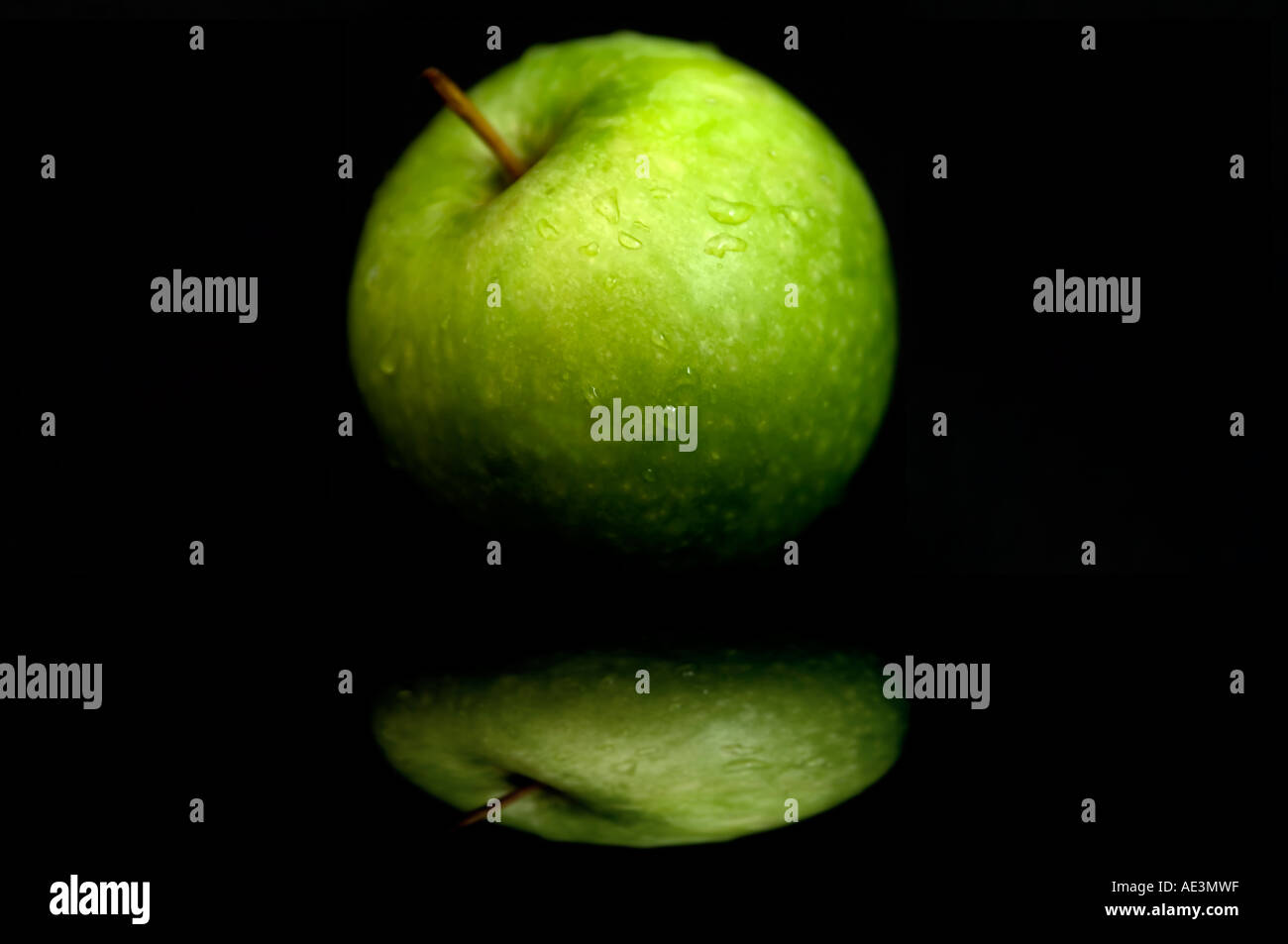 Green Apple on reflective surface noire Banque D'Images