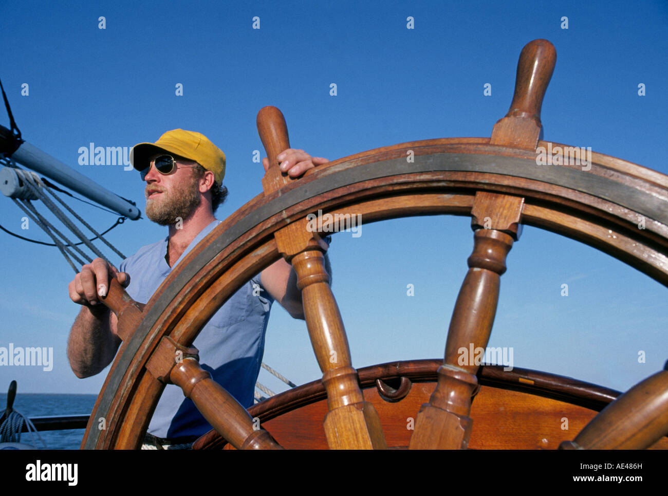 Un marin est à la roue en bois du navire à voile gréé carré Elissa comme elle quitte le port de Galveston Texas Banque D'Images