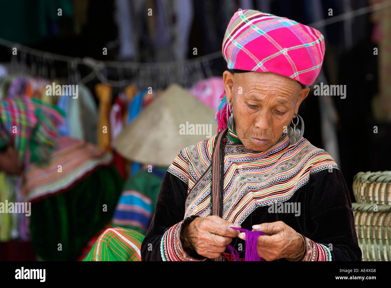 Vieille Femme trie fils colorés Bac Ha marché hilltribe Hmong fleurs colorées de traders nord Vietnam Banque D'Images