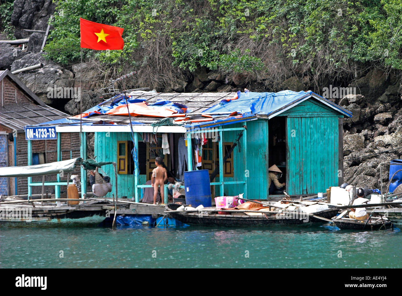 Drapeau vietnamien en vol au dessus du village de pêcheurs flottant maison de pêcheurs de la baie de Halong Vietnam Banque D'Images