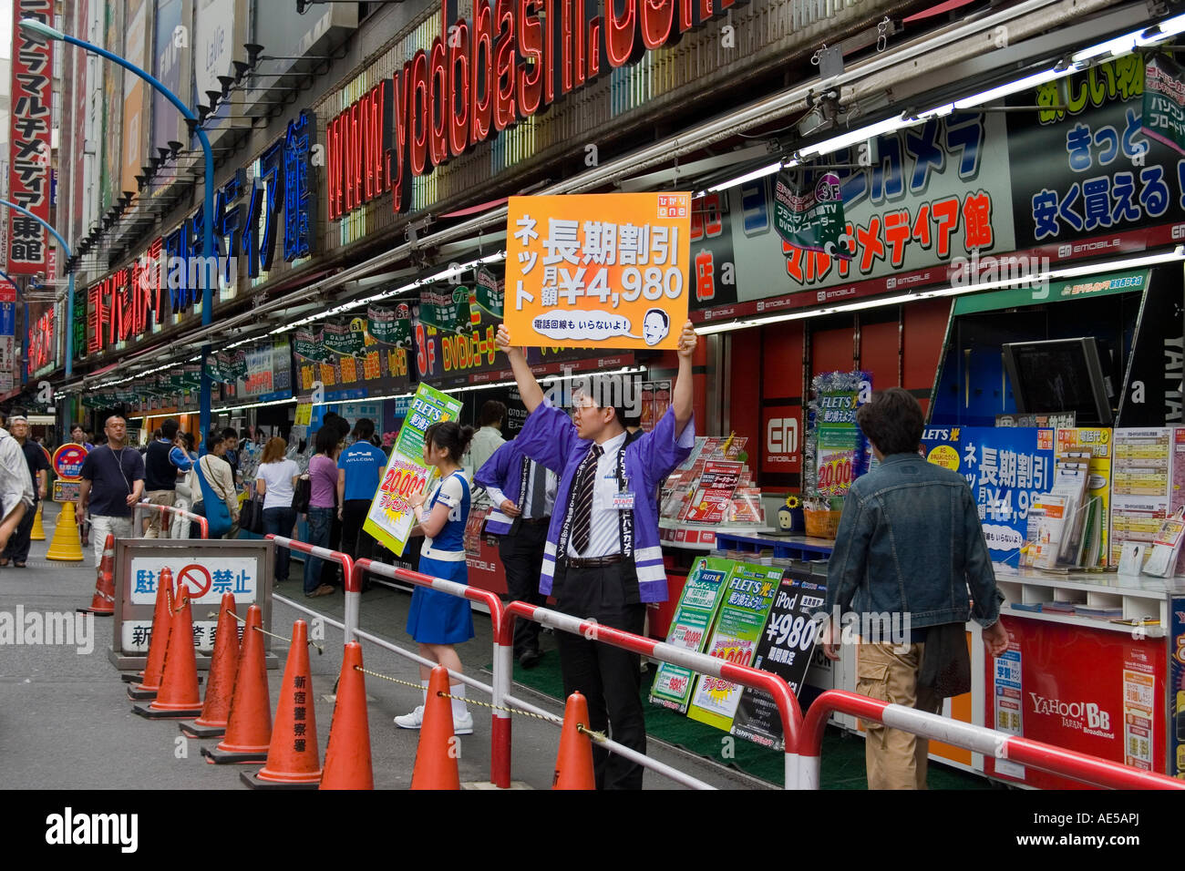 La surcharge visuelle des signes japonais et gens tenant des pancartes de publicité des produits dans un magasin d'électronique à Shinjuku Tokyo Japon Banque D'Images