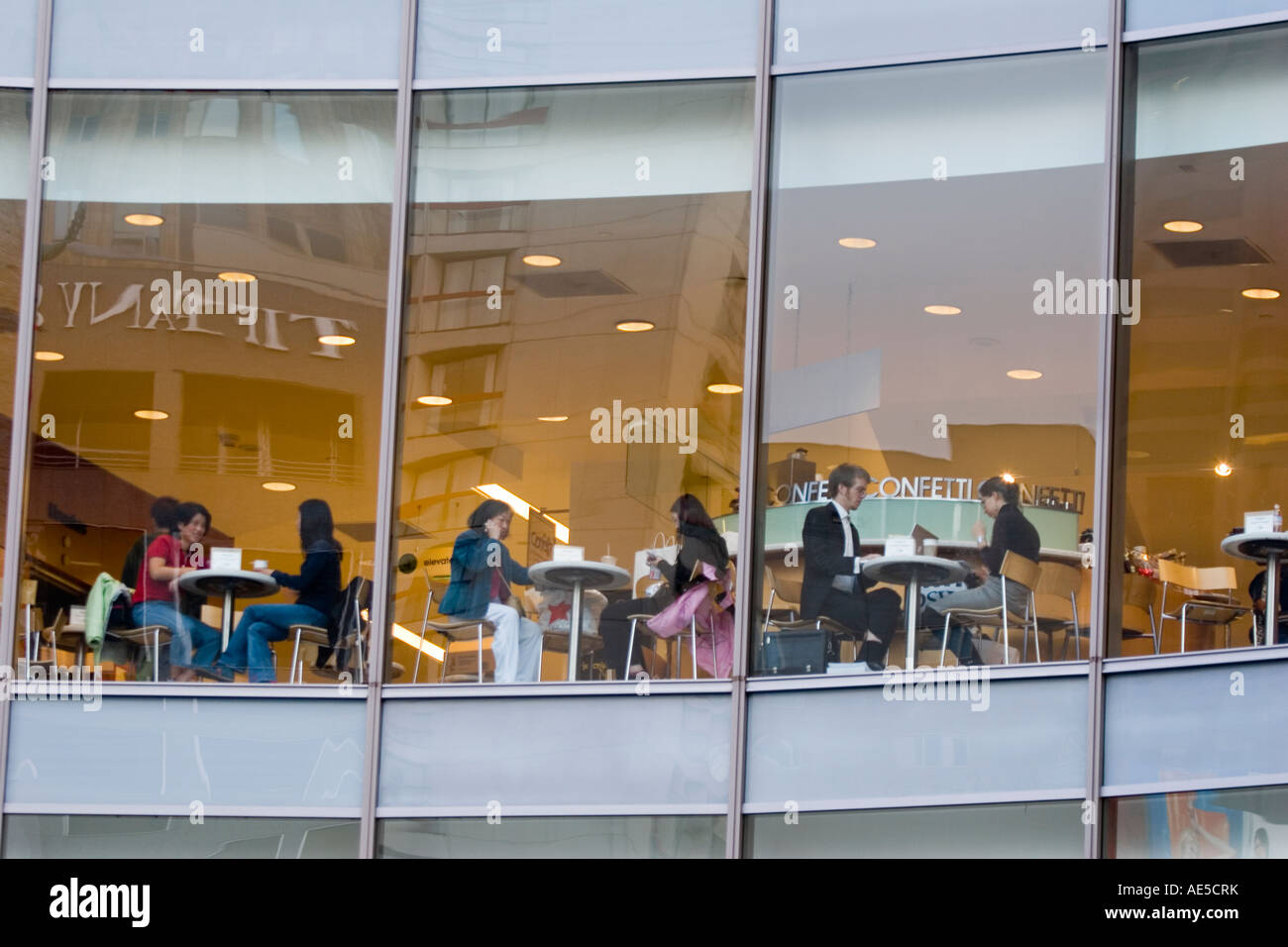 Les personnes qui prennent une pause de shopping au grand magasin cafe comme vu de l'extérieur par l'intermédiaire de windows Banque D'Images