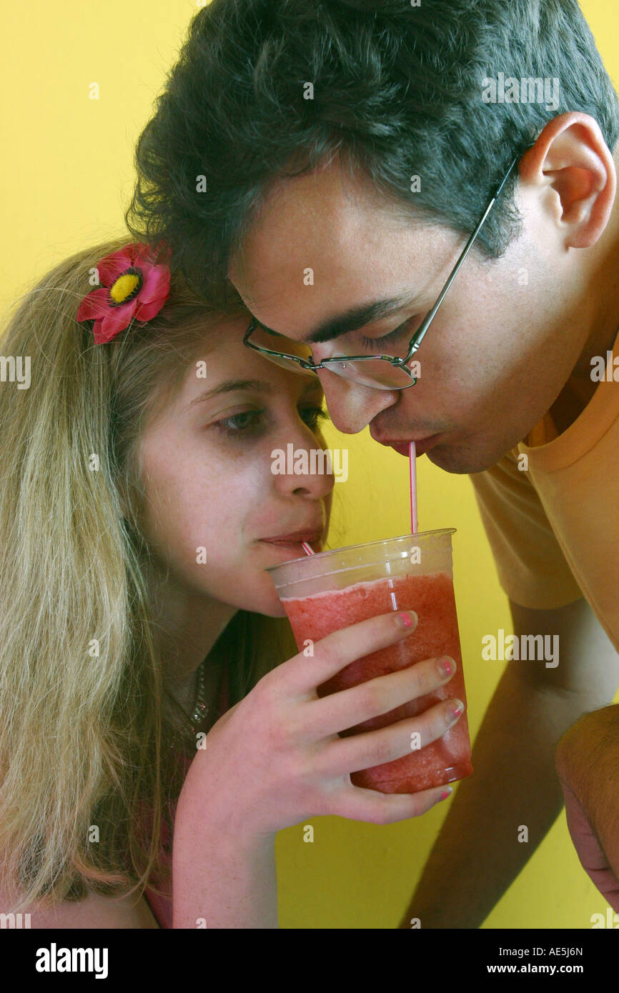 Jeune homme de 20 ans et 19 ans femme couple partageant un smoothie fraise verre avec deux pailles Banque D'Images