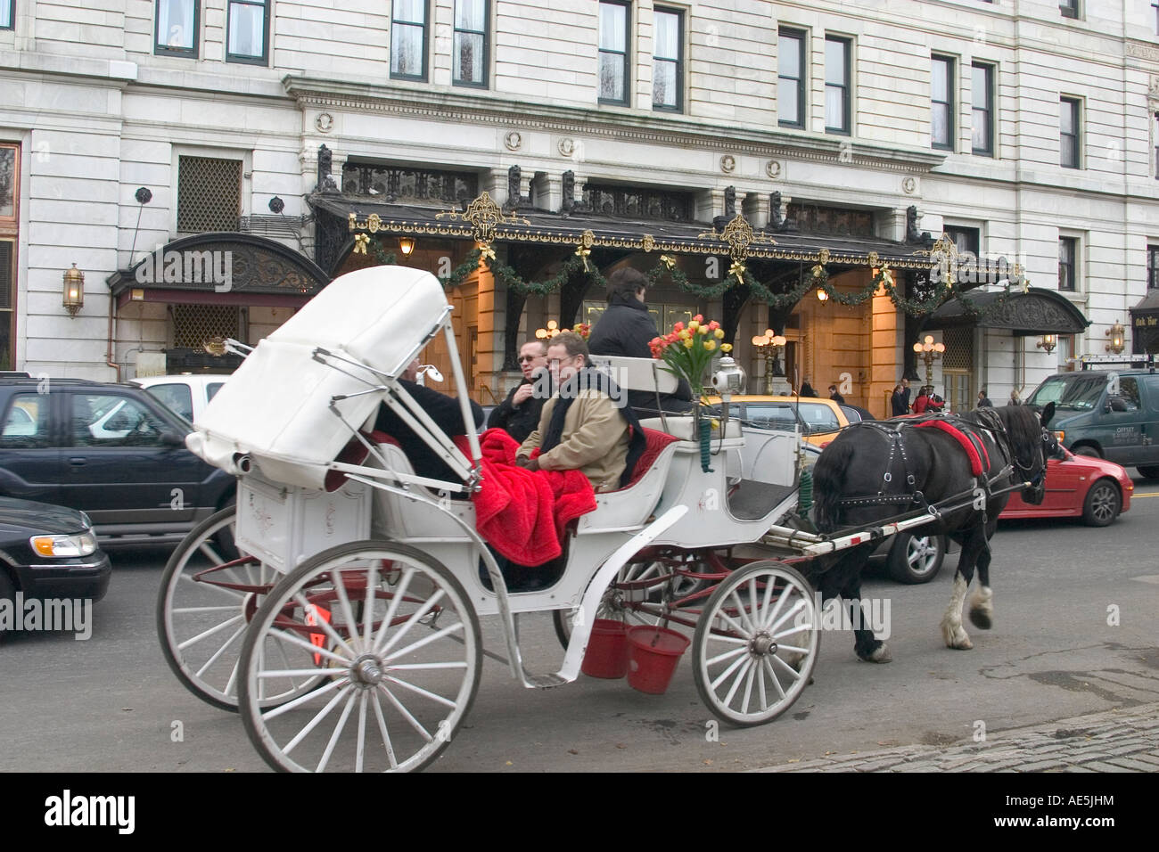 Les touristes à cheval panier roulant par Plaza Hotel à New York le jour de l'hiver froid regroupés dans des écharpes et couvertures Banque D'Images