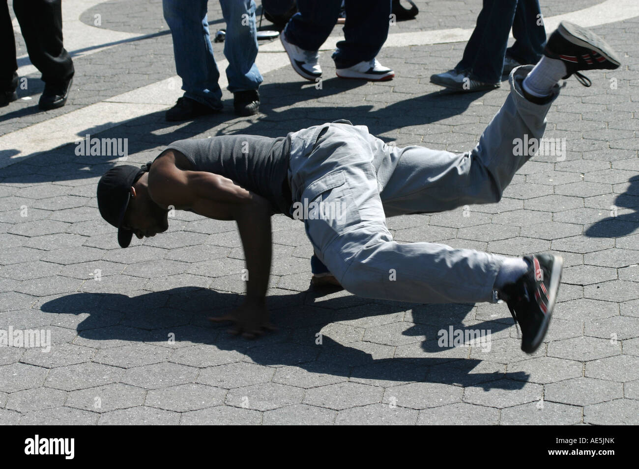 Black man street performer - danse en équilibre sur les mains avec les pieds en l'air et son ombre sur la chaussée Banque D'Images