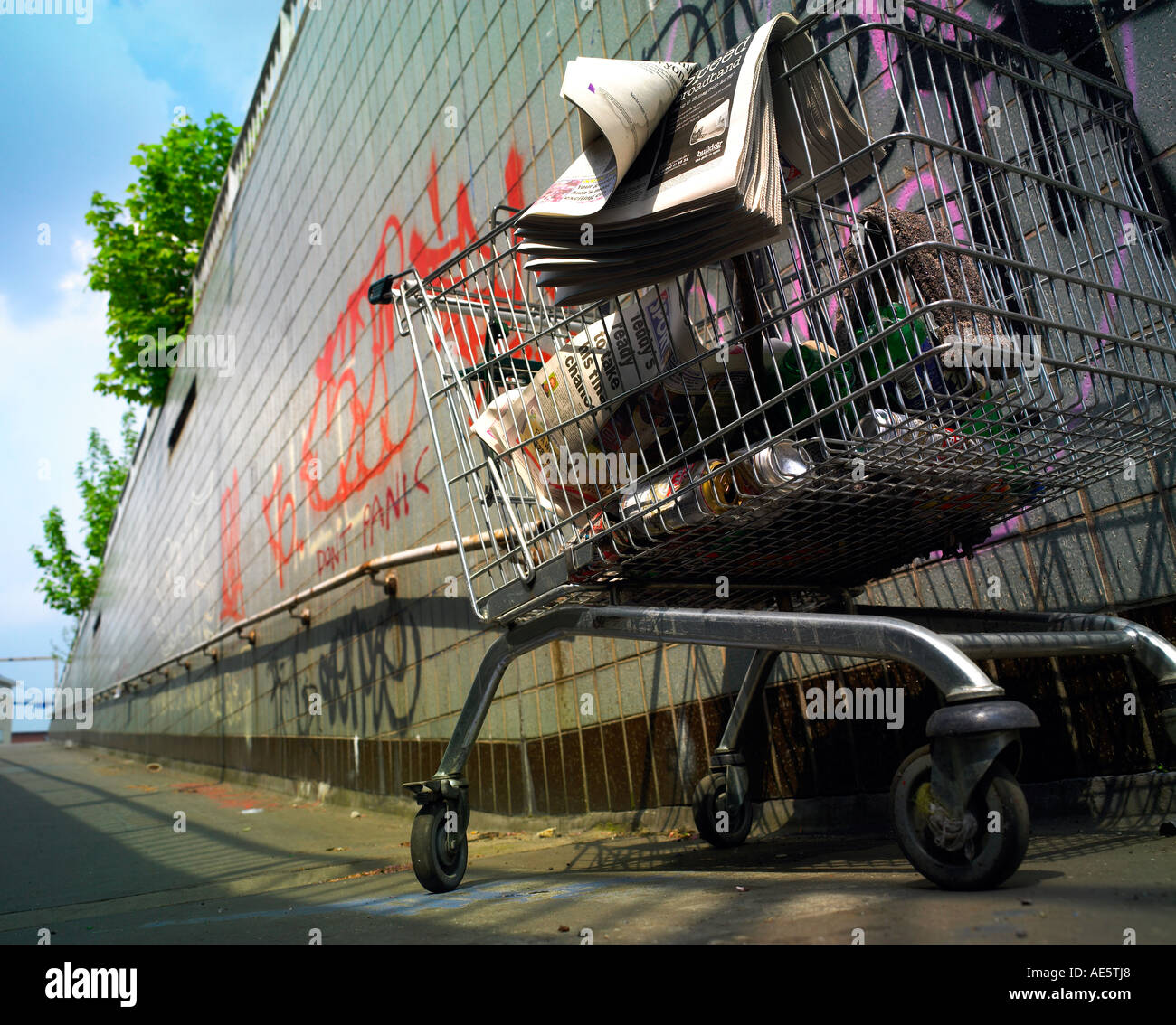 Shopping trolley utilisé par personne sans-abri sur un passage inférieur de Manchester avec graffitti sur mur Banque D'Images