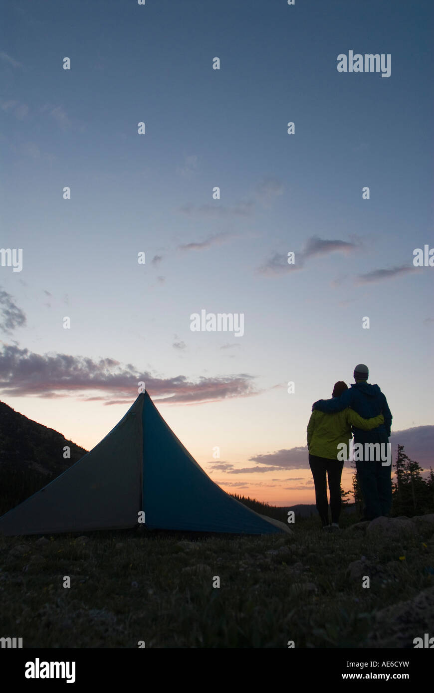 Camping Couple hugging et tente de regarder le coucher du soleil Banque D'Images