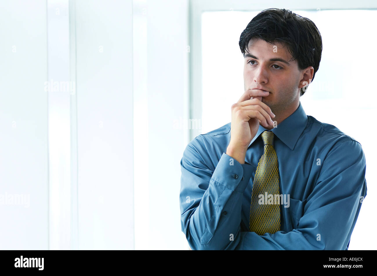 Portrait of young businessman in office environnement, pensive et réfléchie, à l'appareil photo Banque D'Images