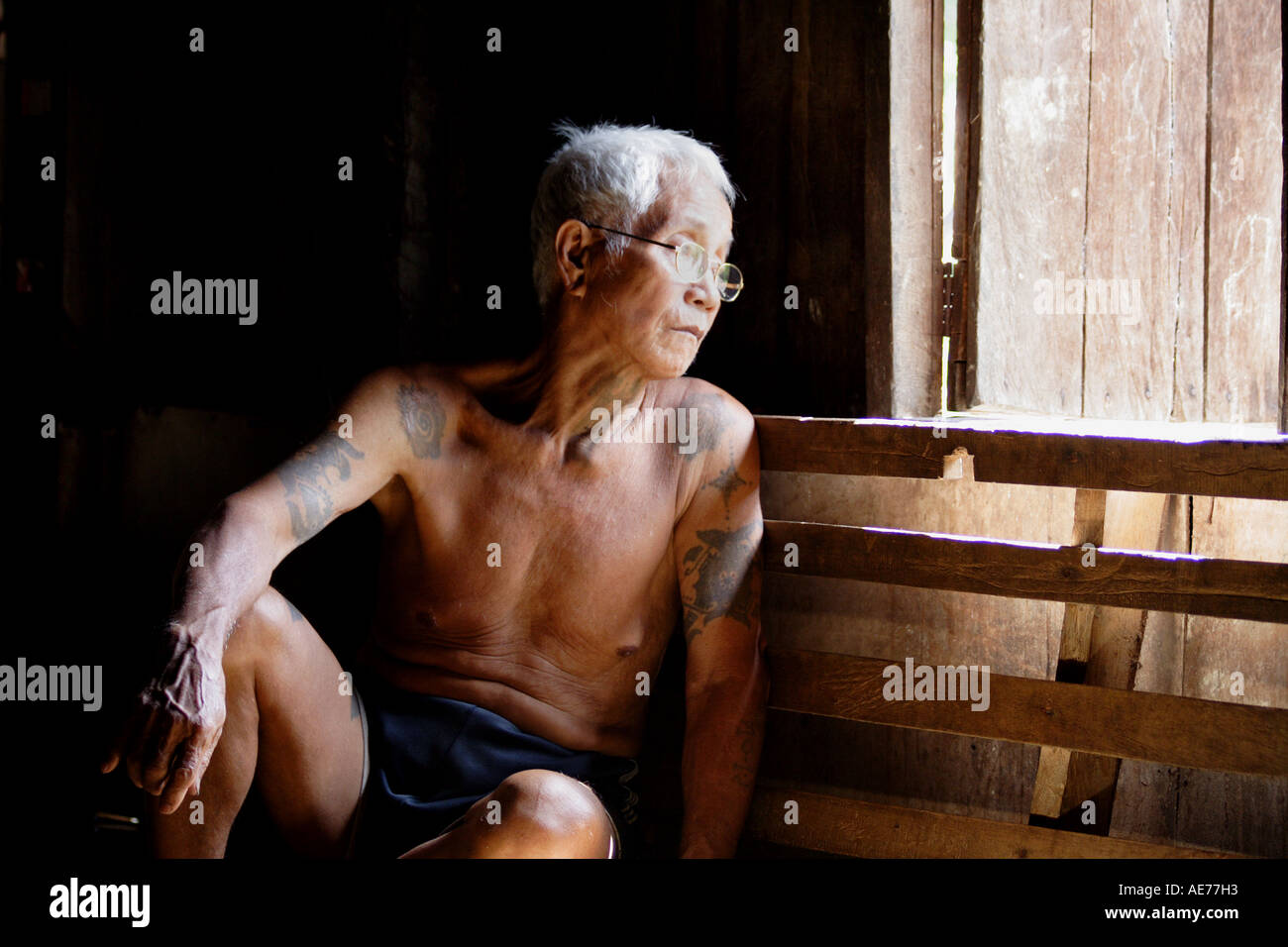 Vieil homme assis dans la longue piscine véranda de Rumah Uluyong, une longue maison traditionnelle Iban, Kapit, Sarawak, Bornéo, Malaisie Banque D'Images