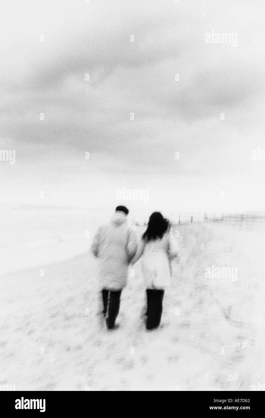 Couple en train de marcher sur une plage en hiver Banque D'Images