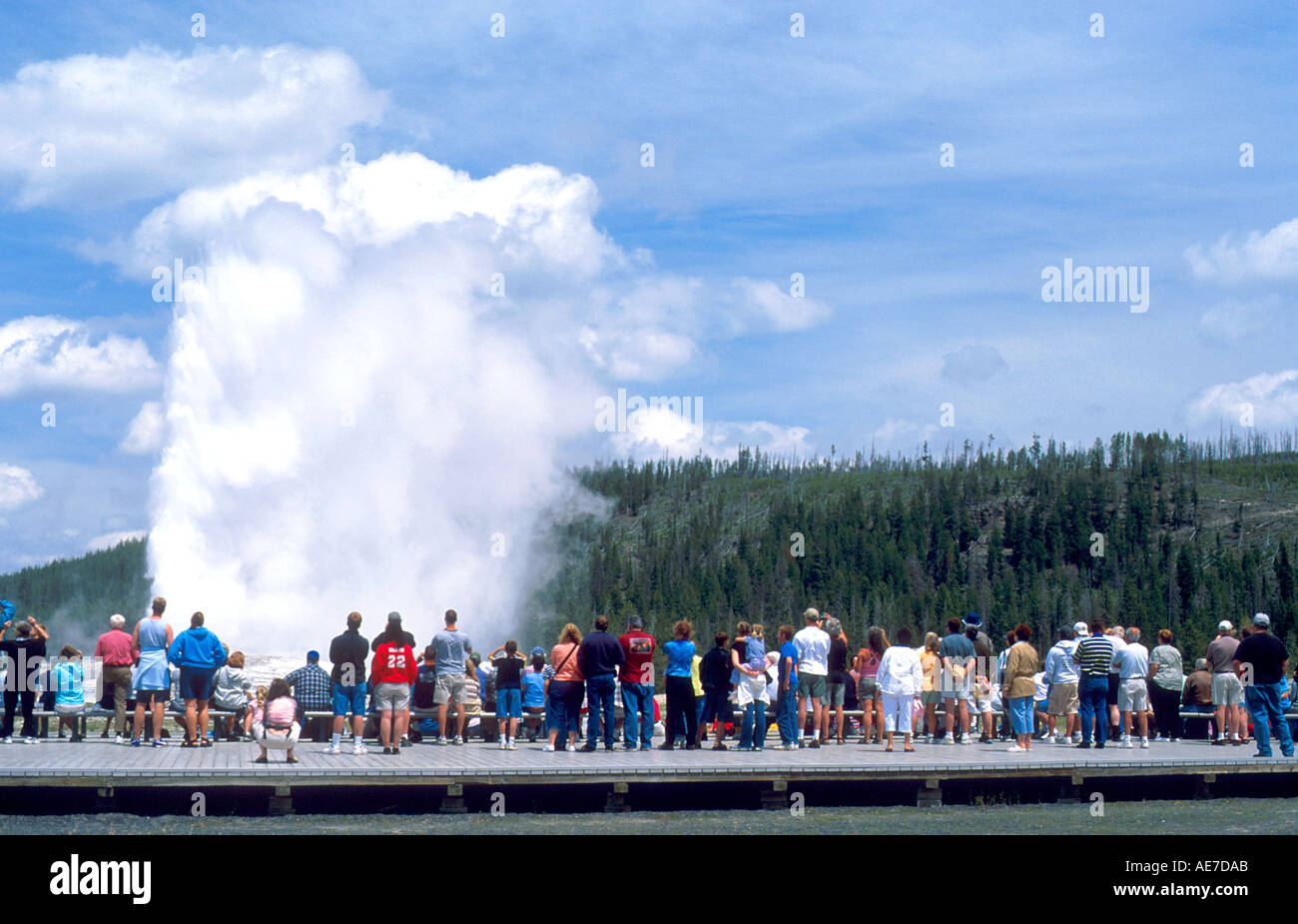 Les touristes visitant Old Faithful Geyser lors d'éruption dans le Parc National de Yellowstone au Wyoming Banque D'Images