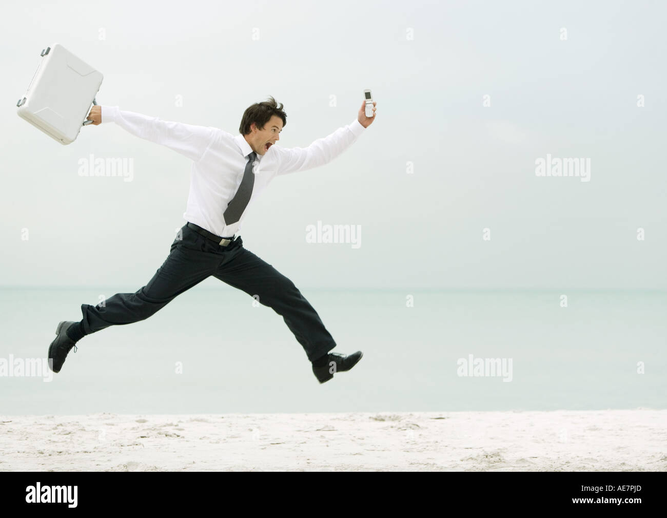 Businessman courir et sauter sur la plage Banque D'Images