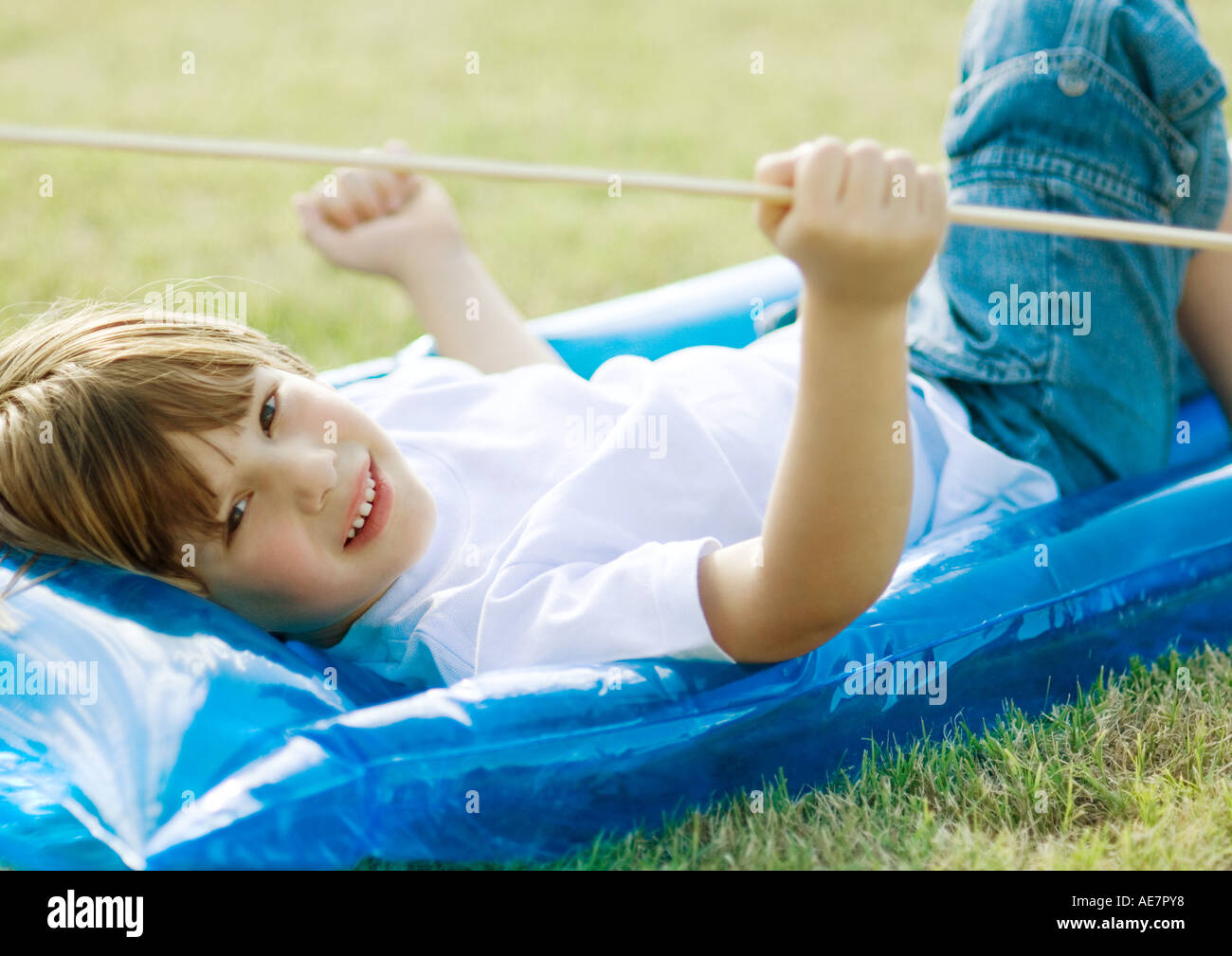 Petit garçon couché sur radeau pneumatique, sur l'herbe Banque D'Images