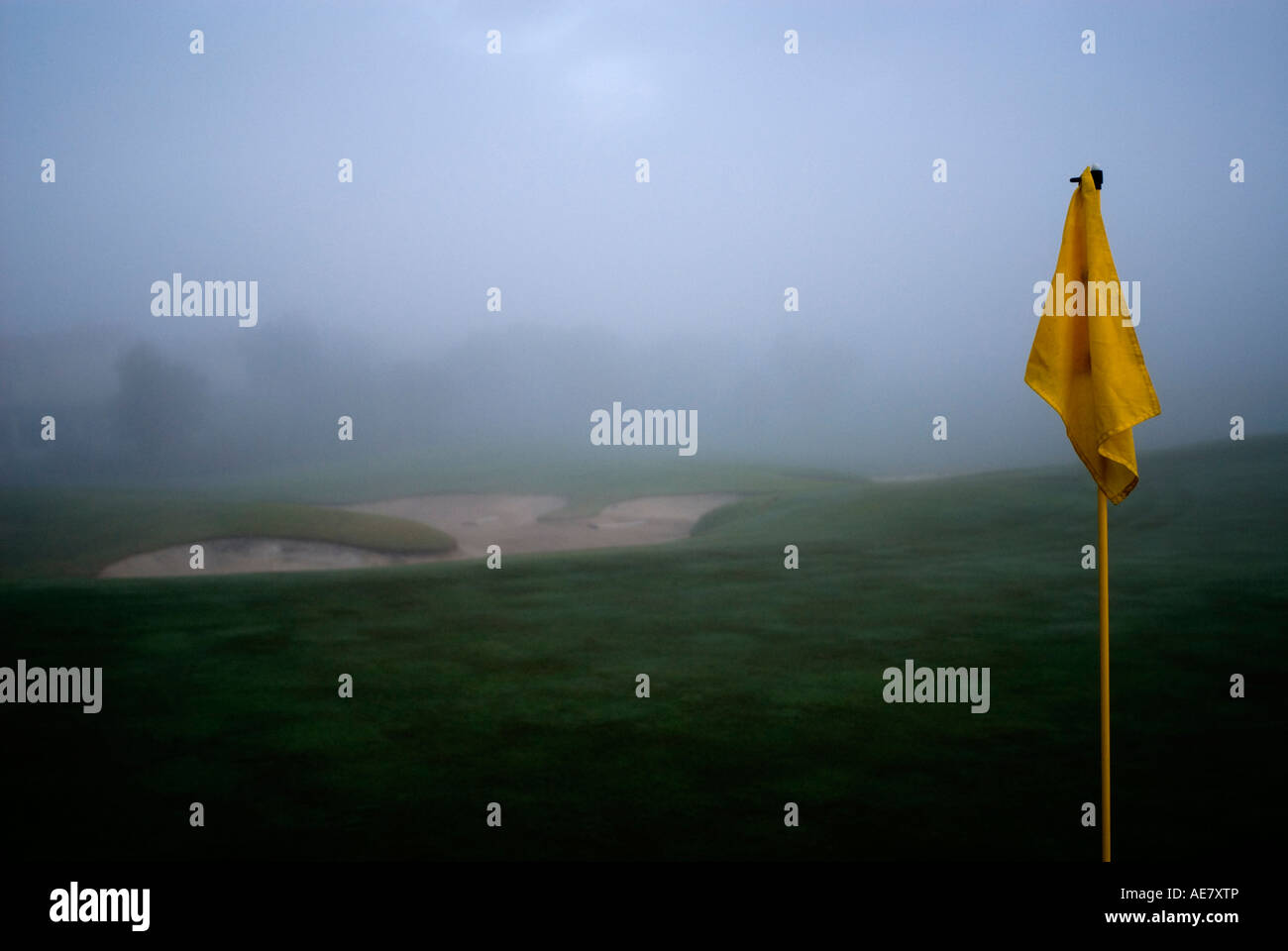 Golf avec golf flag jaune en premier plan, le sable bunker en arrière-plan, brume matinale Banque D'Images